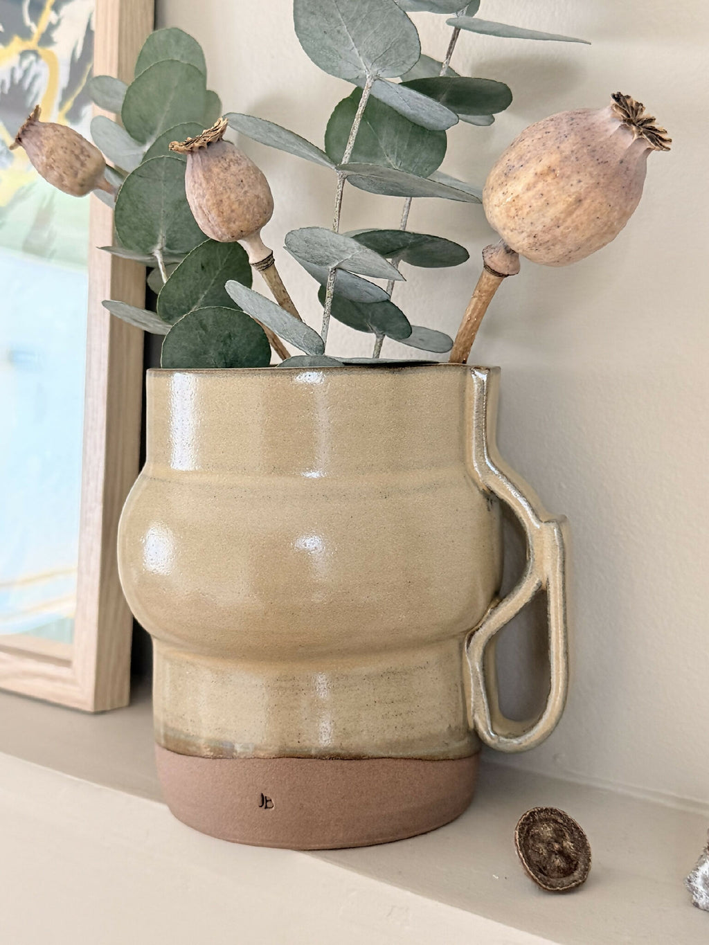 Vase céramique beige à anse, fond brun, tige décorative avec feuilles et petites boules sèches