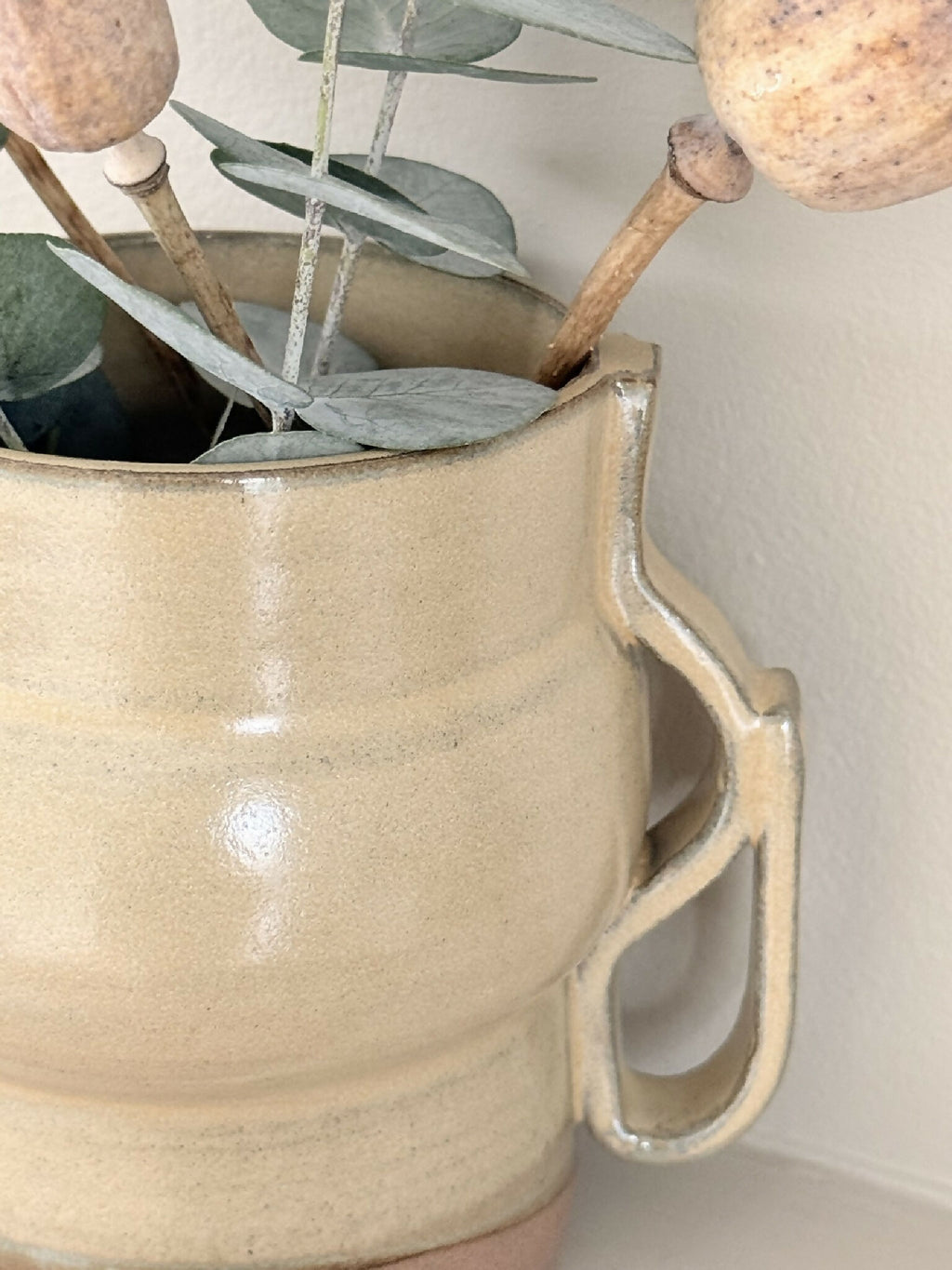 Vase en céramique beige brillant, anse enveloppante, bord en relief et tige décorative
