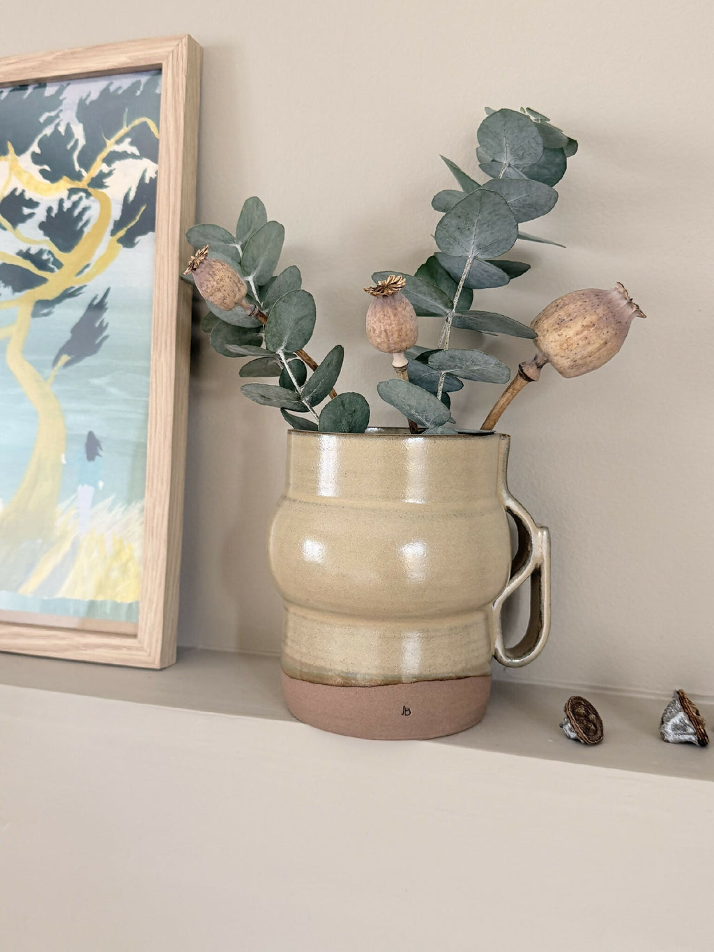 Vase en céramique beige avec anse, base brun, orné de branches vertes et têtes séchées