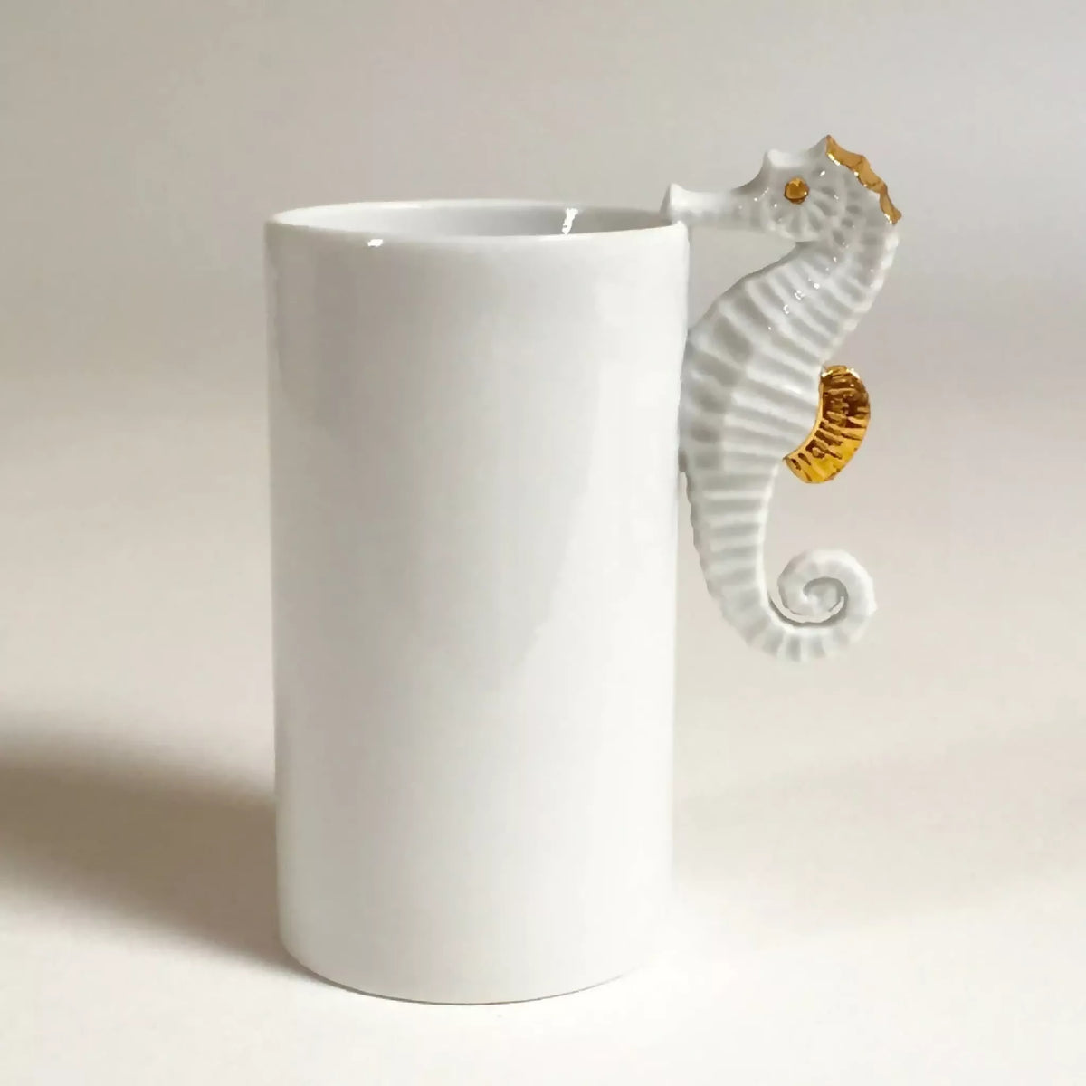 Vase cylindrique blanc avec hippocampe en relief et accents dorés sur le côté