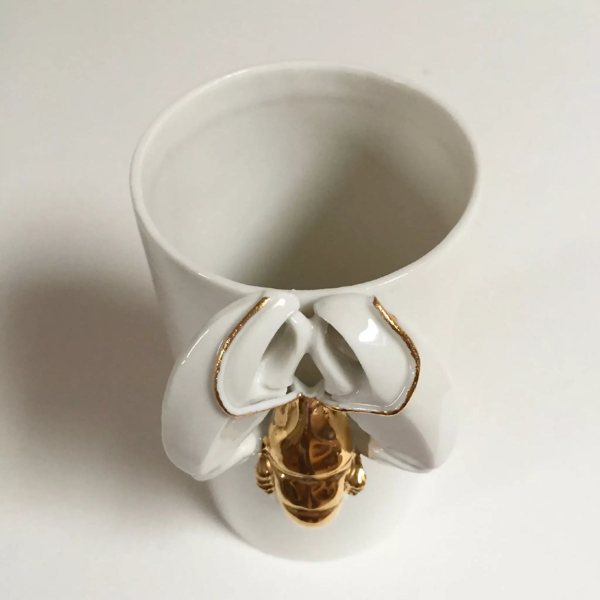 Vase homard blanc, ouverture supérieure, figurine dorée au centre.