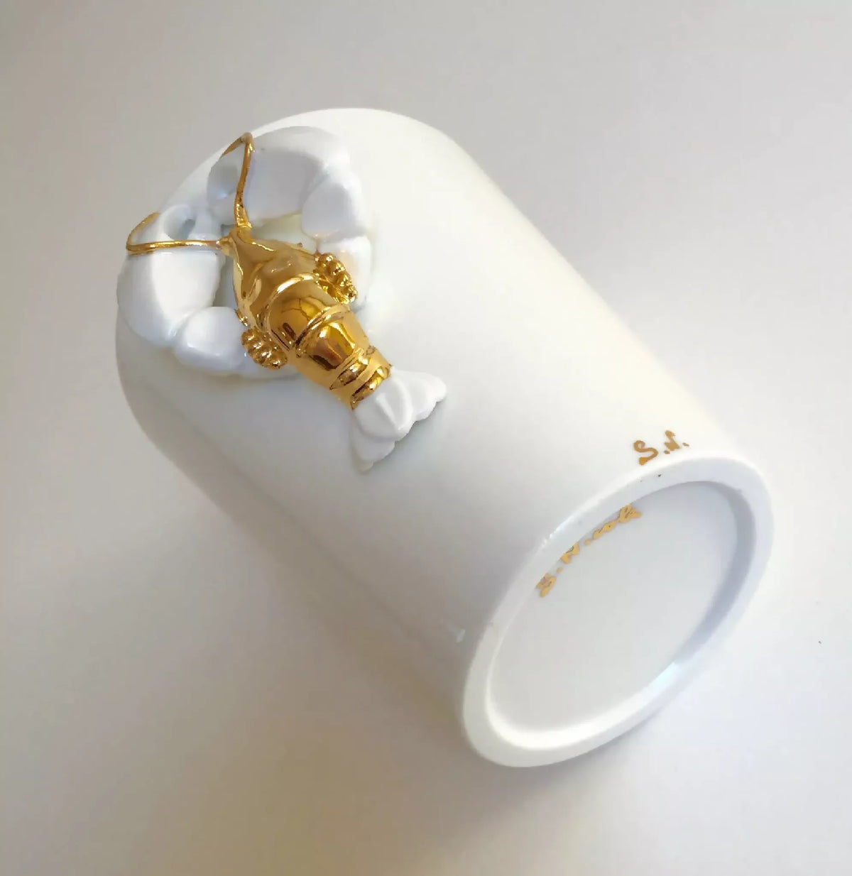 Vase homard blanc, ouverture sur le côté, figurine dorée sur pinces blanches.