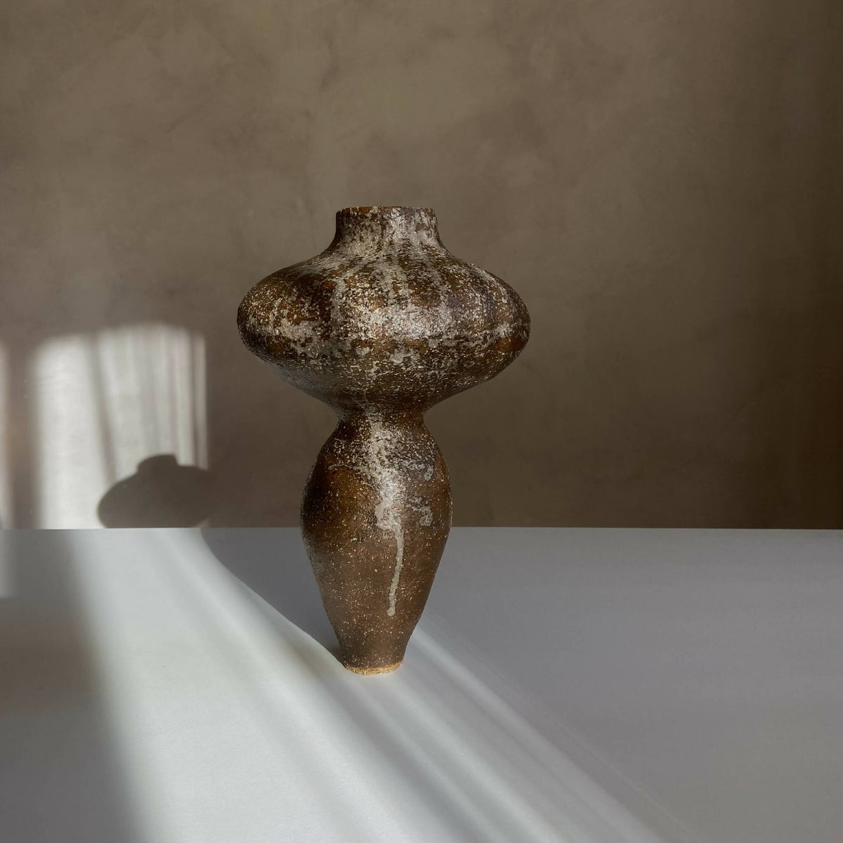 Vase sculptural brun foncé tacheté, silhouette arrondie et long goulot