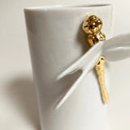 Vase blanc avec ailes de libellule blanches et pièce dorée près du col.