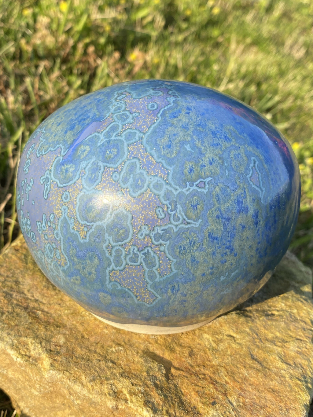 Pierre décorative ovale bleue veinée, reflets nacrés, vue latérale.