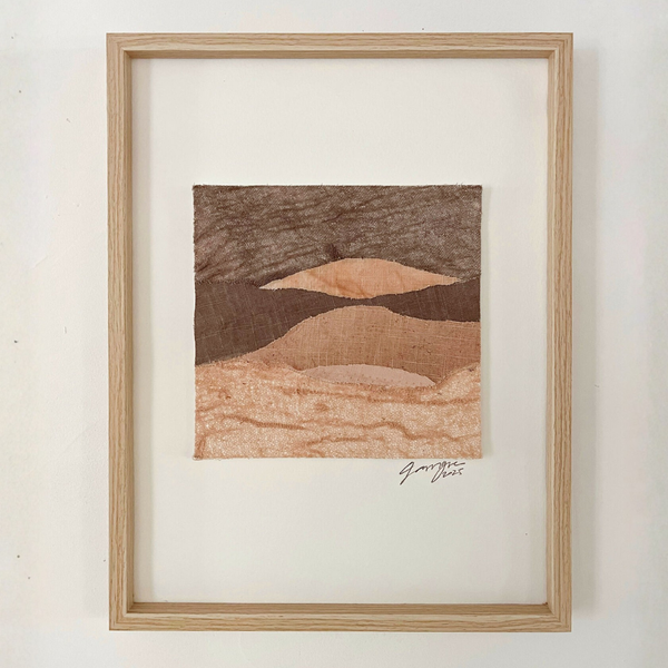 Collage textile encadré en bois clair, paysage abstrait de collines aux tons bruns et beiges.