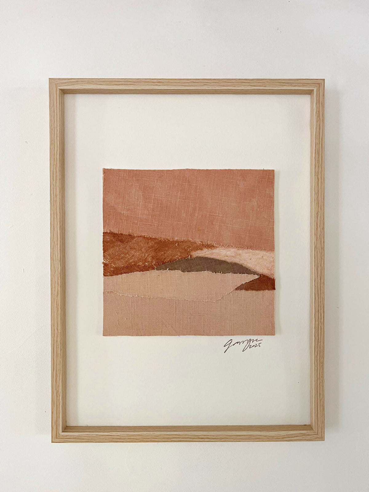 Collage textile abstrait en cadre bois clair, tons terre cuite et beige, signature.