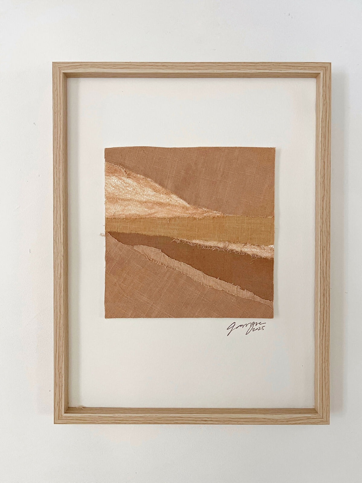 Collage textile encadré, composition de tissus marron et beige avec signature en bas à droite.