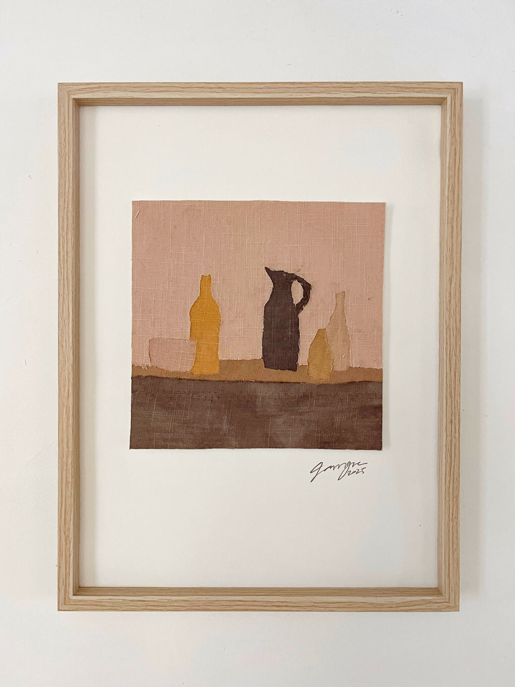 Tableau textile encadré avec silhouette de bouteilles et pots sur fond ocre et brun.