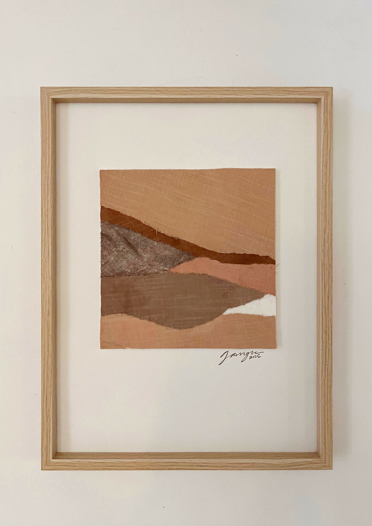 Collage textile abstrait en cadre bois clair, formes en tons beige et brun, signature.
