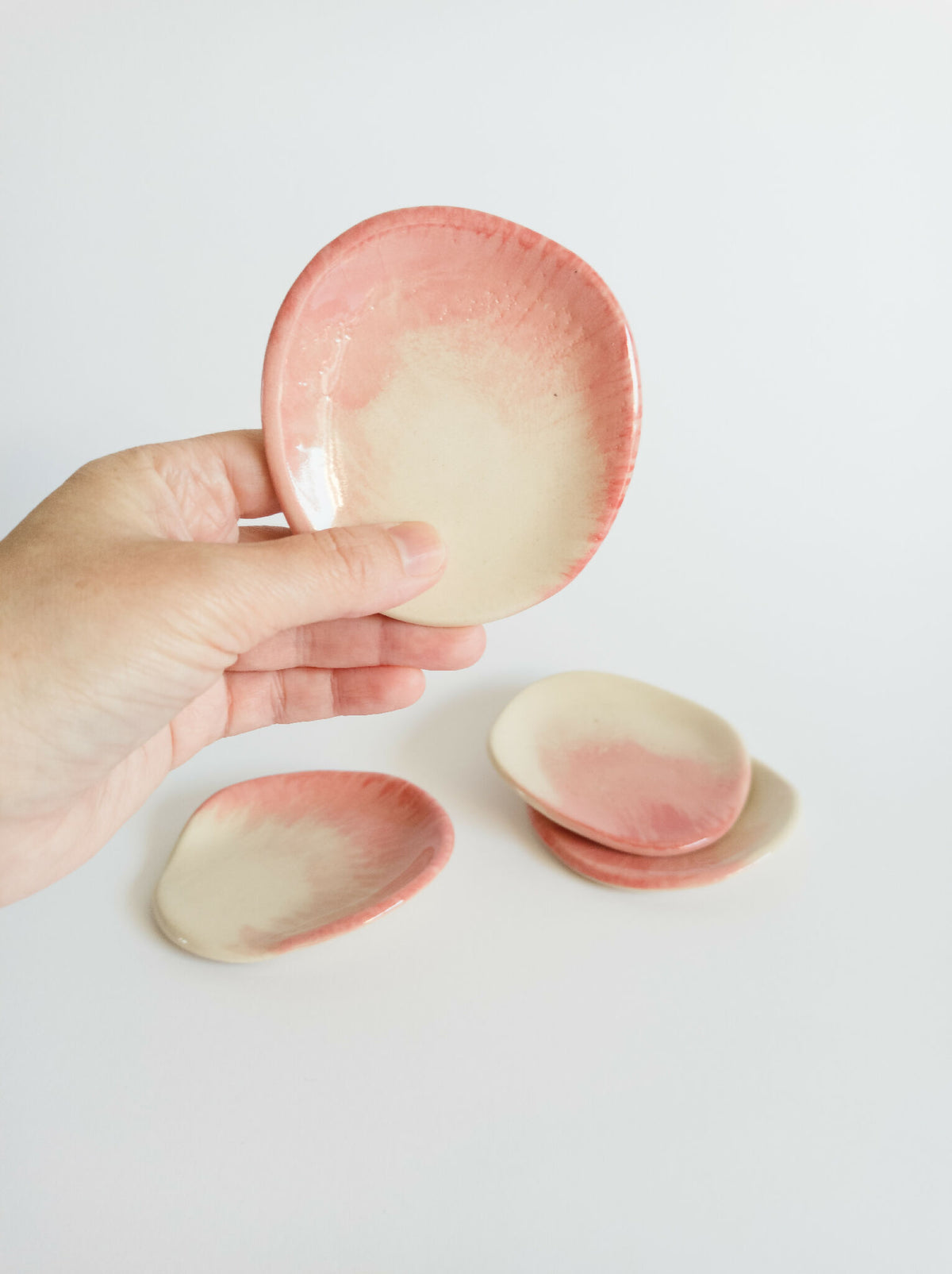 Repose-cuillères en grès ovales rose pâle et beige, prise par une main