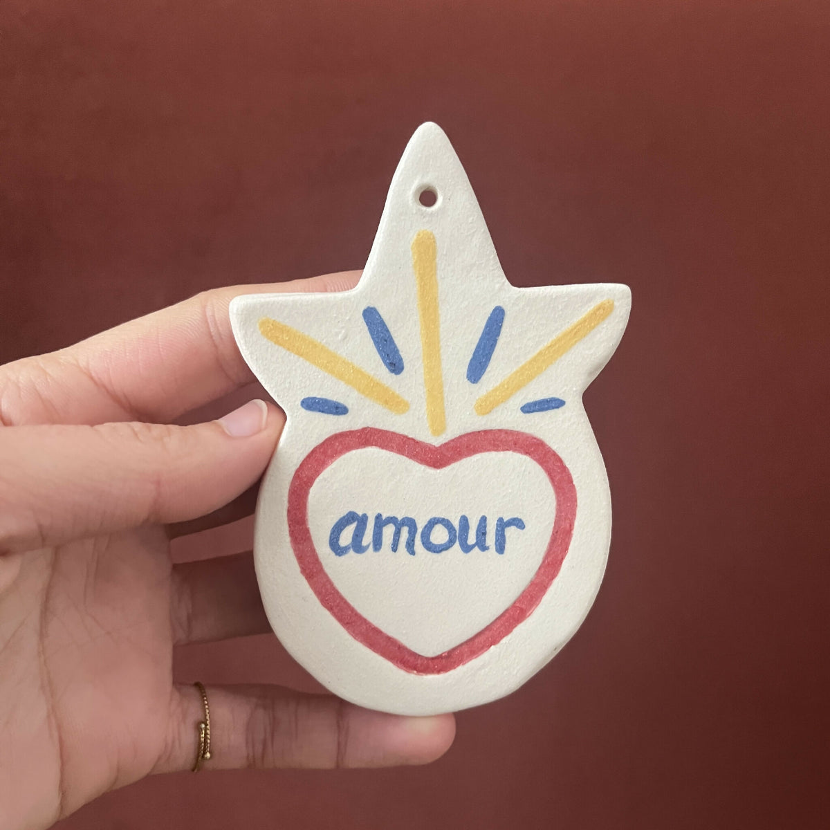 Ex-voto en forme d’étoile, cœur « amour » rouge, rayons multicolores au sommet.