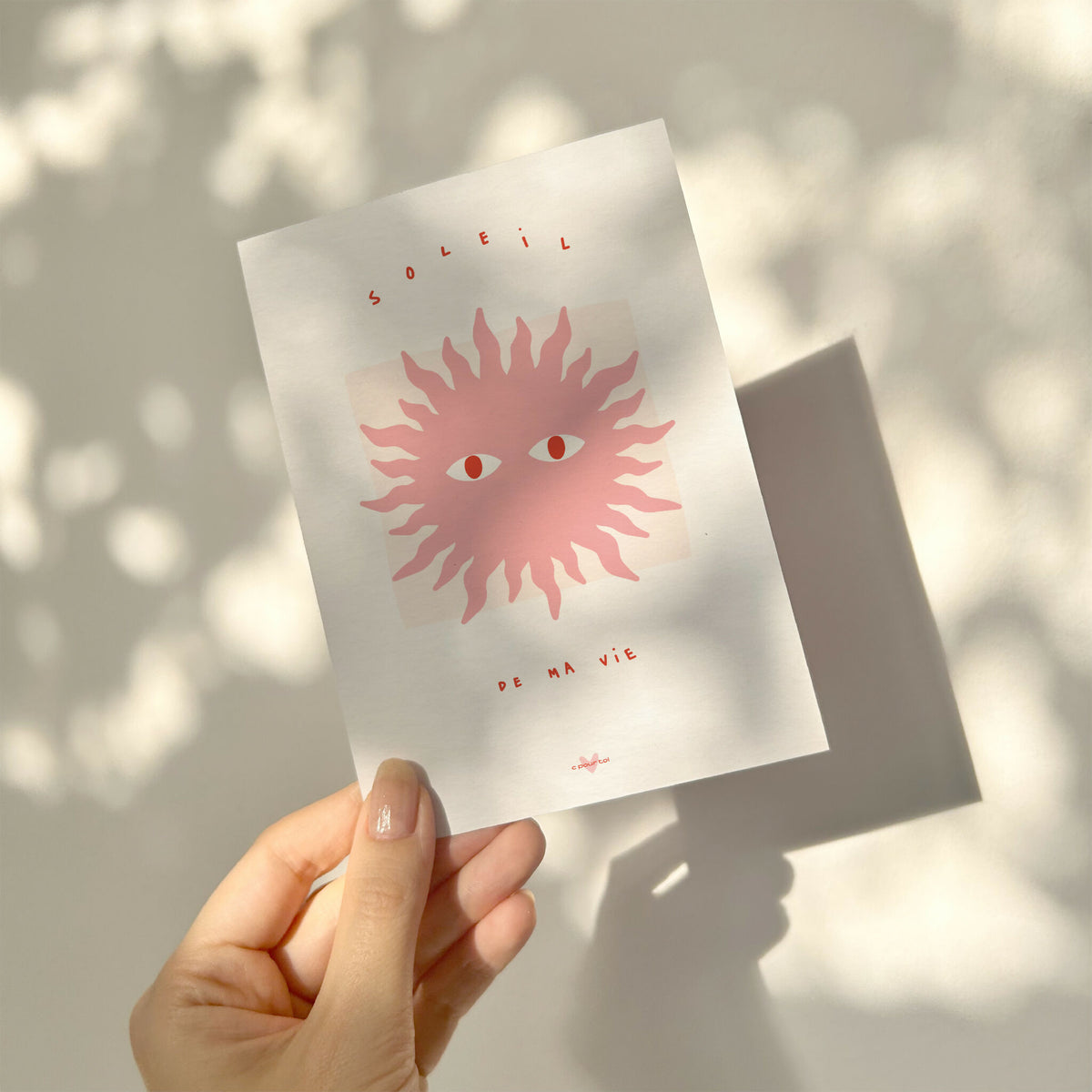 Carte à message blanche avec soleil rose, visages et « de ma vie », tenue en main