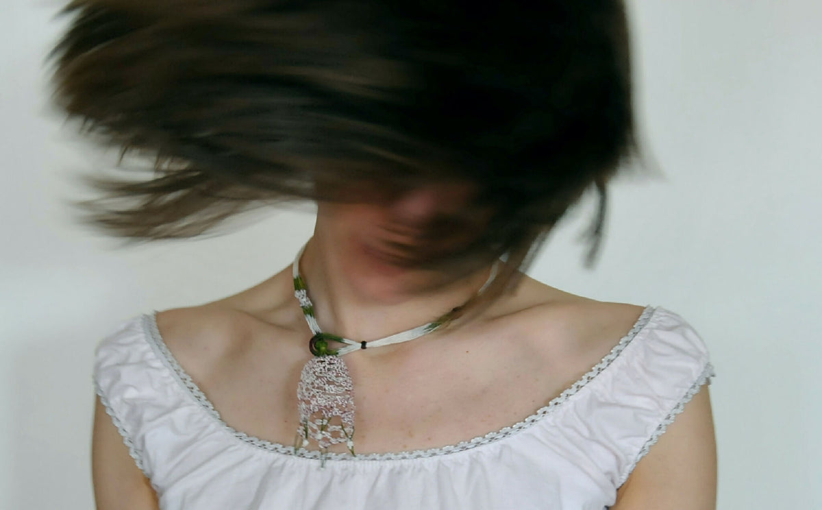 Collier en soie avec pendentif tulipe violet et vert, porté autour du cou.