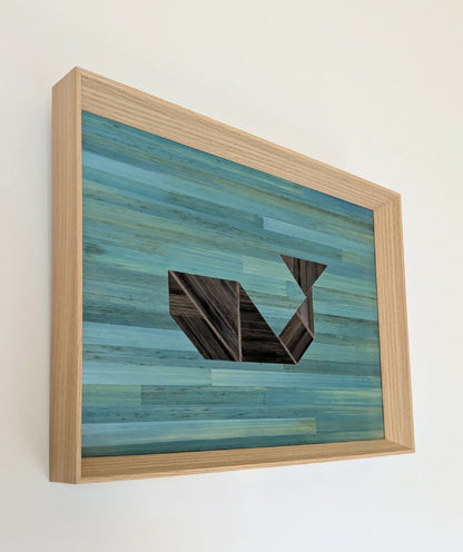Tableau encadré en bois clair, marqueterie de paille bleue claire et motif géométrique gris.