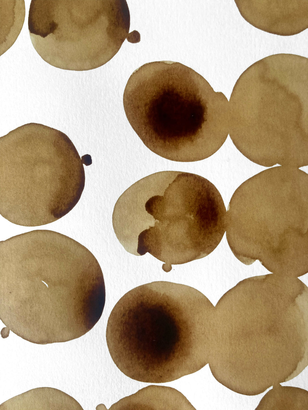 Taches de café brunes sur papier, formes circulaires superposées.