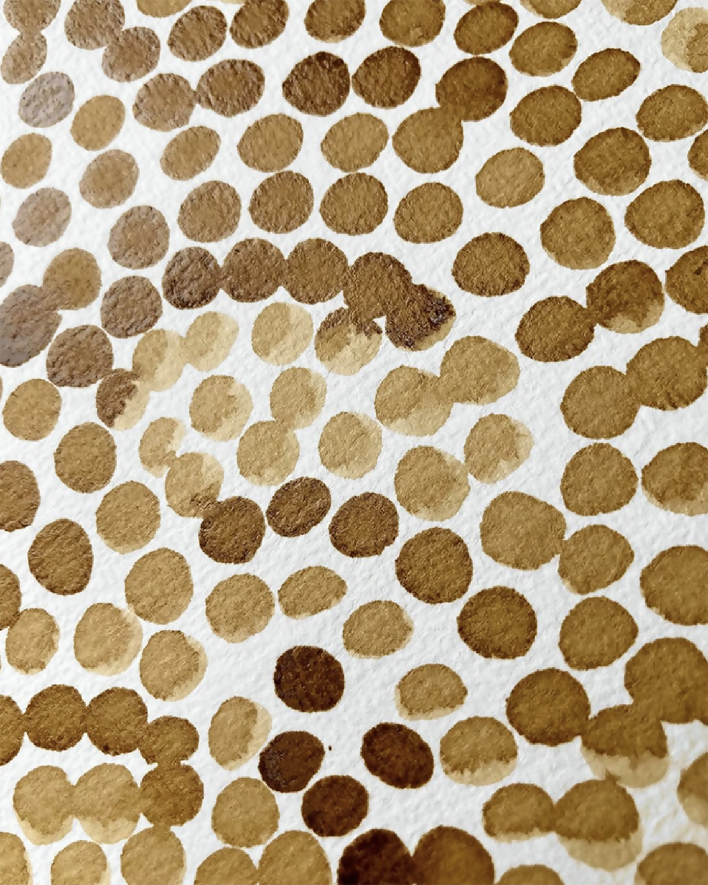 Tableau encadré, gros plan sur points de café ocre et bruns sur fond crème.
