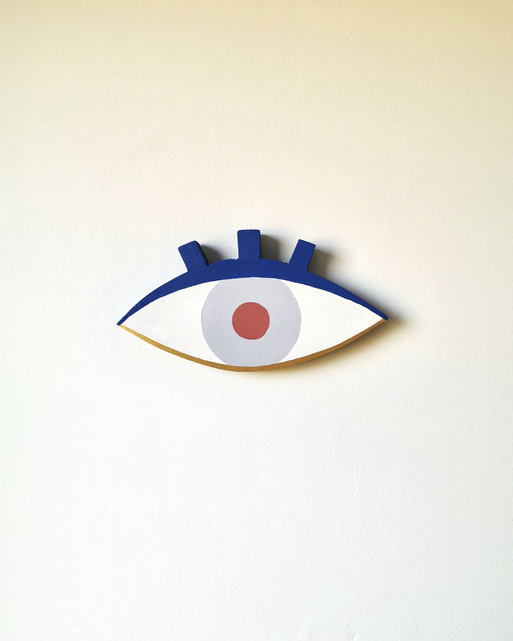 Petit œil en bois peint, contour bleu foncé, iris bleu clair et pupille orange.