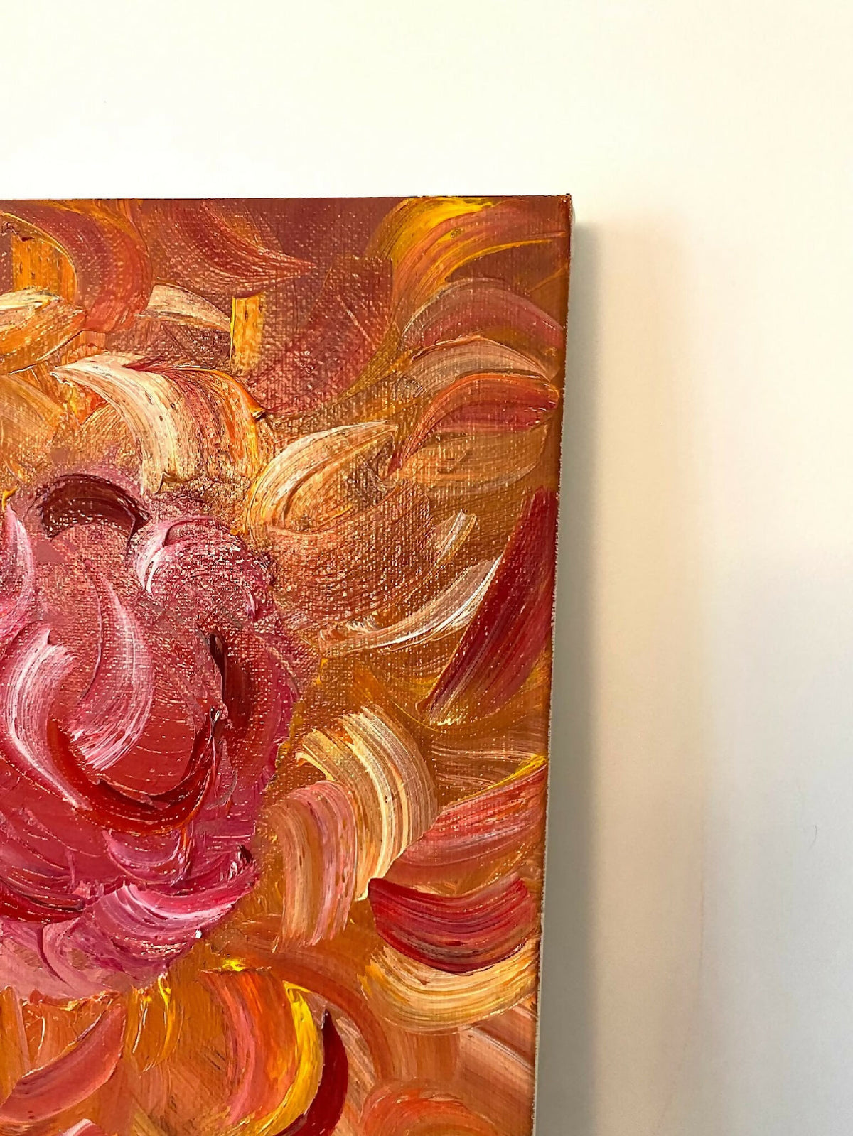 Gros plan sur tableau décoratif abstrait : tourbillon rose et touches orange, effet matière.