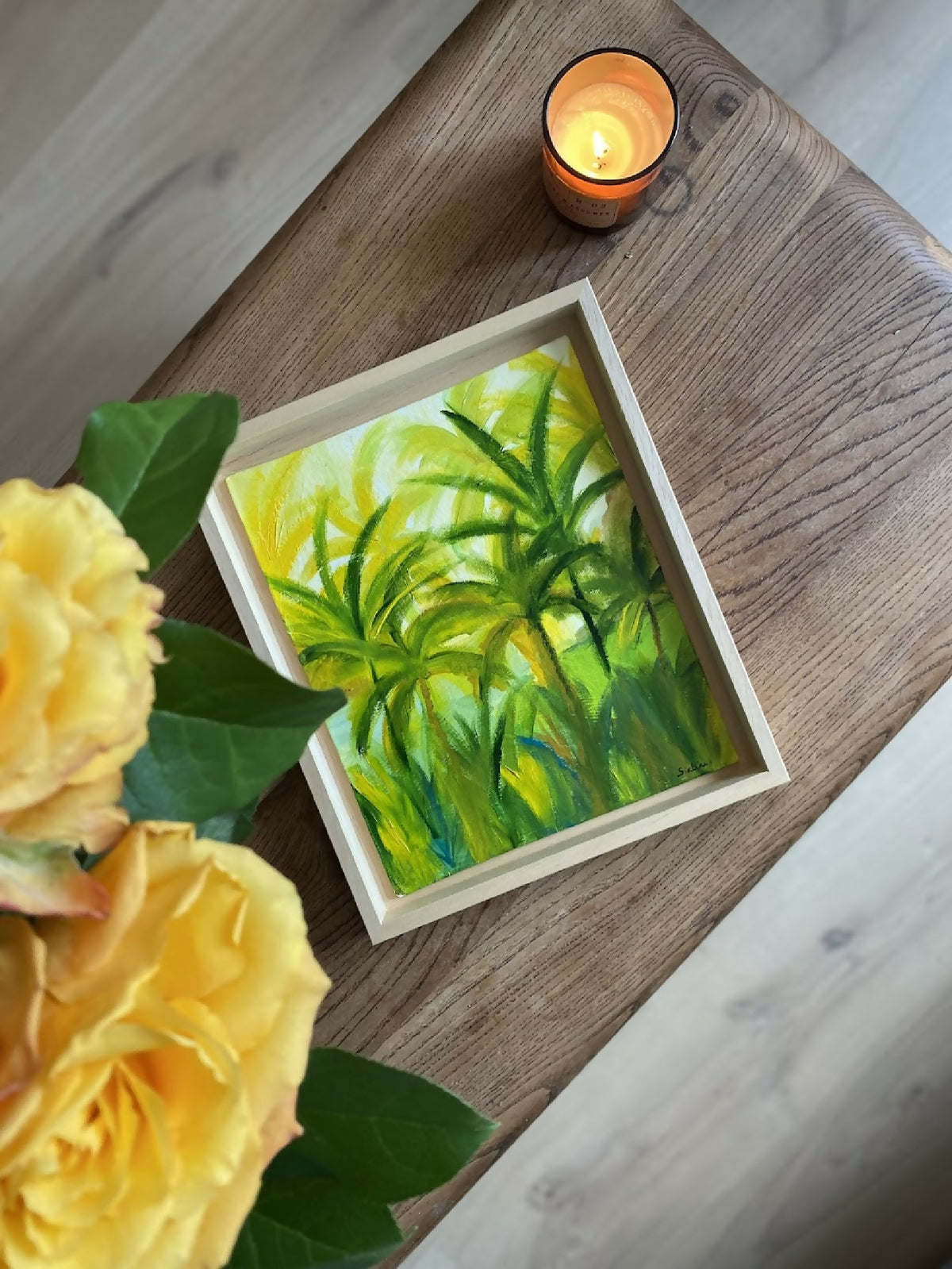 Tableau encadré de palmiers tropicaux vert et jaune, aperçu en angle sur plancher.