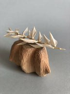 Petit socle sculpté beige avec branche de pointes florales, relief strié visible