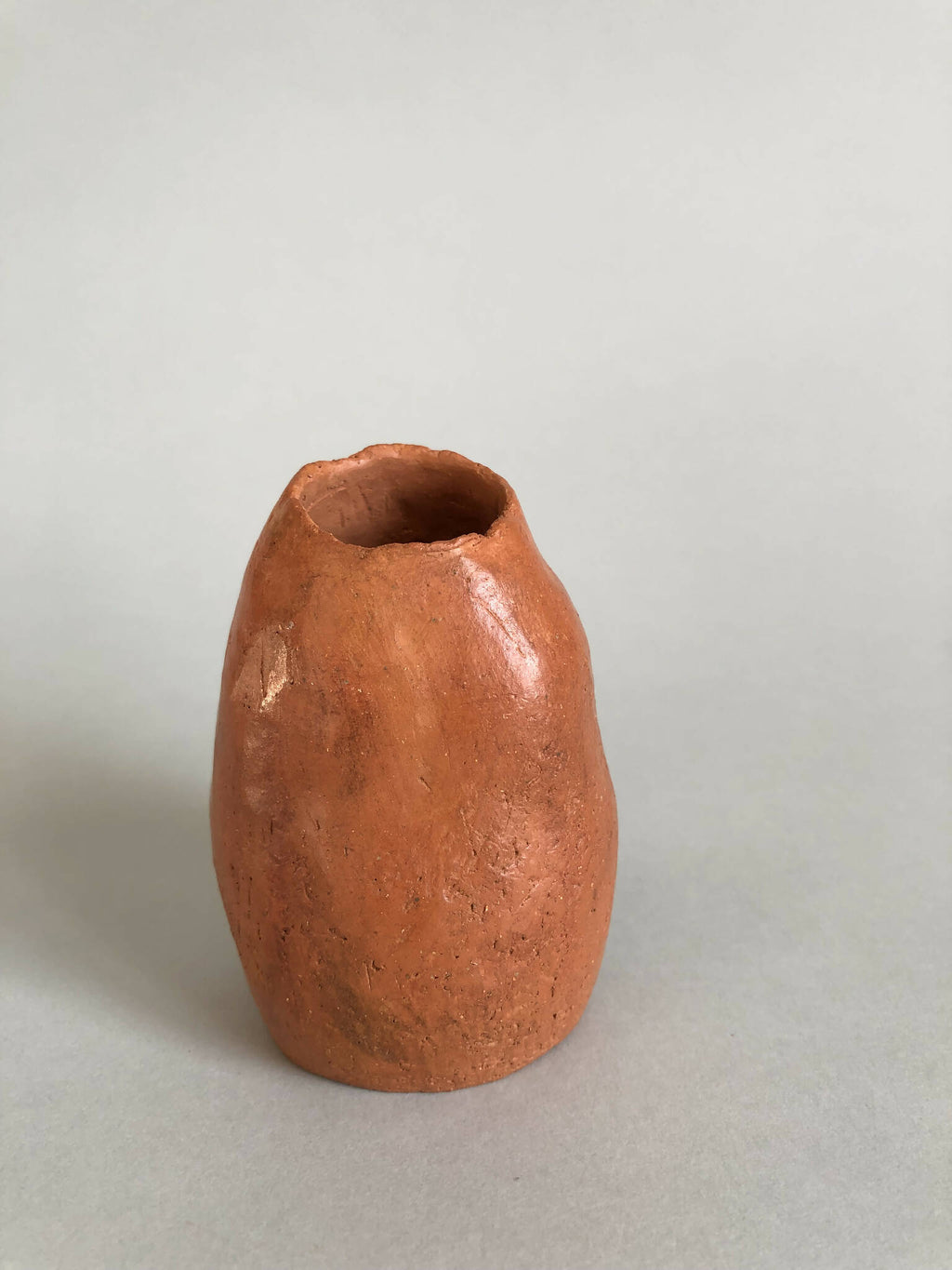 Petit vase en terre cuite orange, forme ovoïde, ouverture large.
