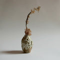Petit vase ROC en céramique texturée beige, avec brins secs sur le haut.