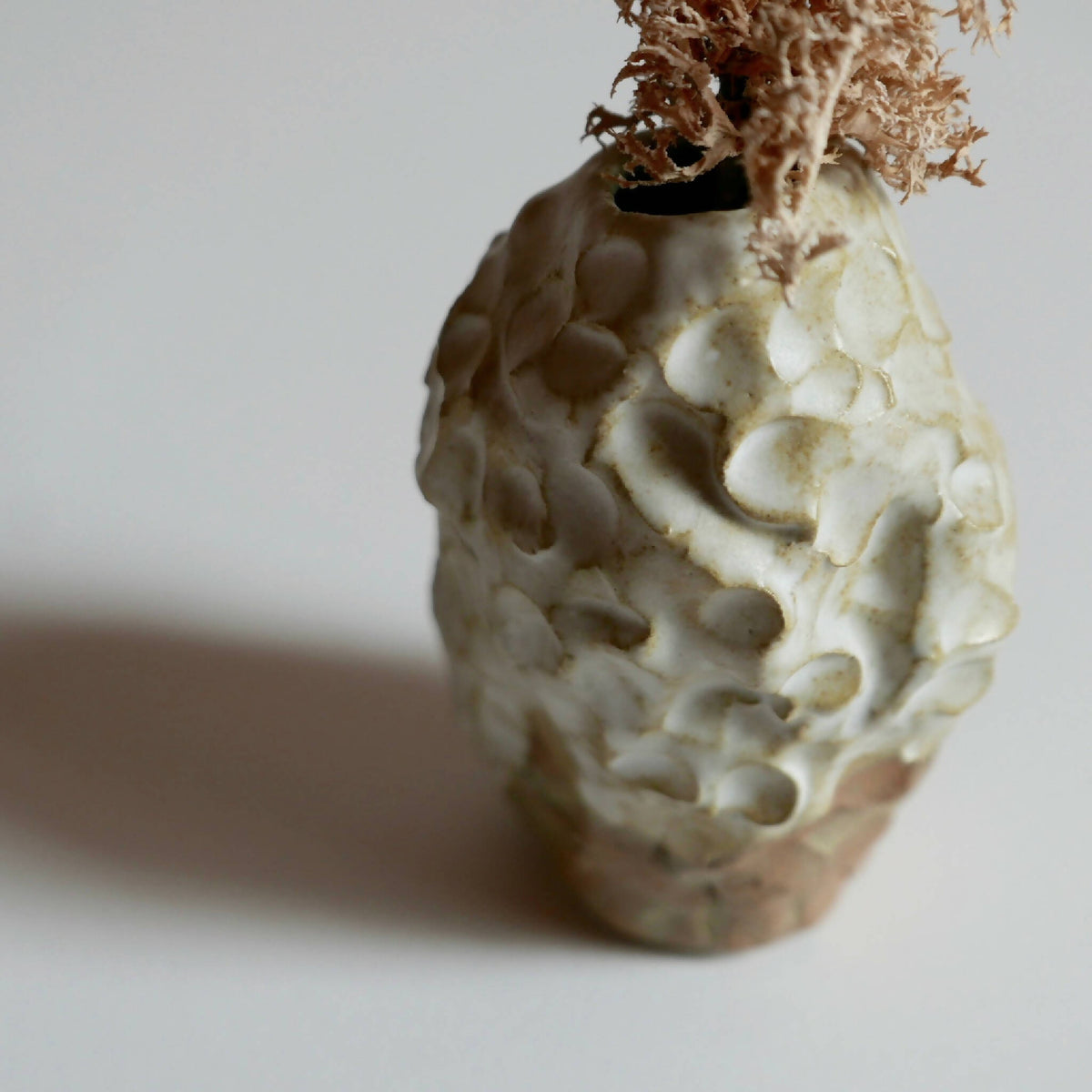 Petit vase ROC en céramique texturée, ouverture en haut et brins secs.