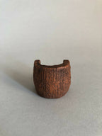 Petit objet concave en matière brune texturée, ouverture en haut