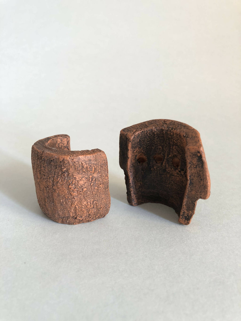 Deux petites pièces cuivre rouillé ajourées, formes concaves, vue côte à côte.
