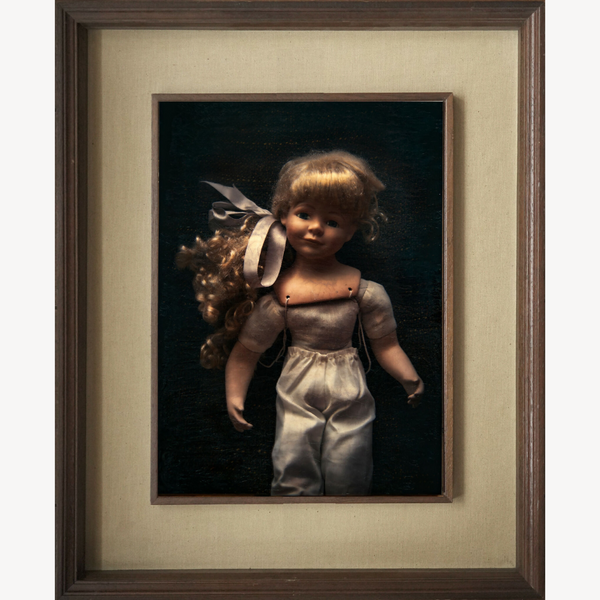Grand cadre du portrait d’une poupée brune, robe argent satin et ruban noir