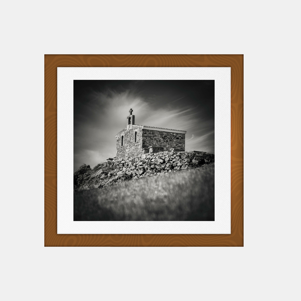 Photographie noir et blanc encadrée, chapelle de pierre sur une colline.
