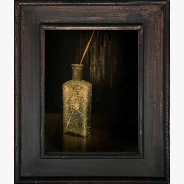Nature morte encadrée avec bouteille ancienne jaune, tige dorée au bouchon.