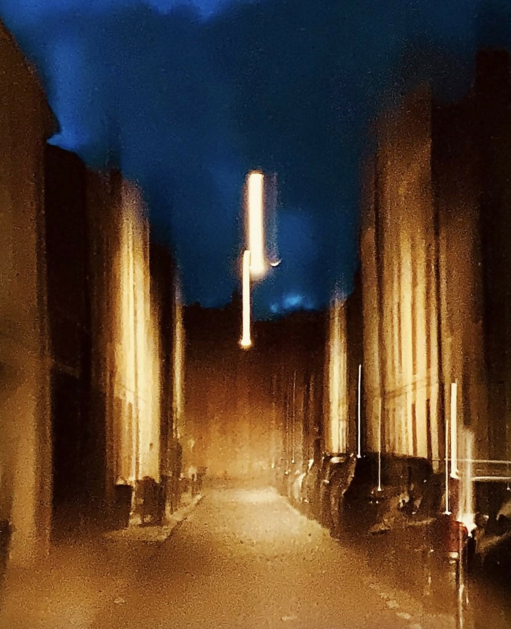 Livre de photographies : allée sombre encadrée de murs, lampes et lumière au fond.