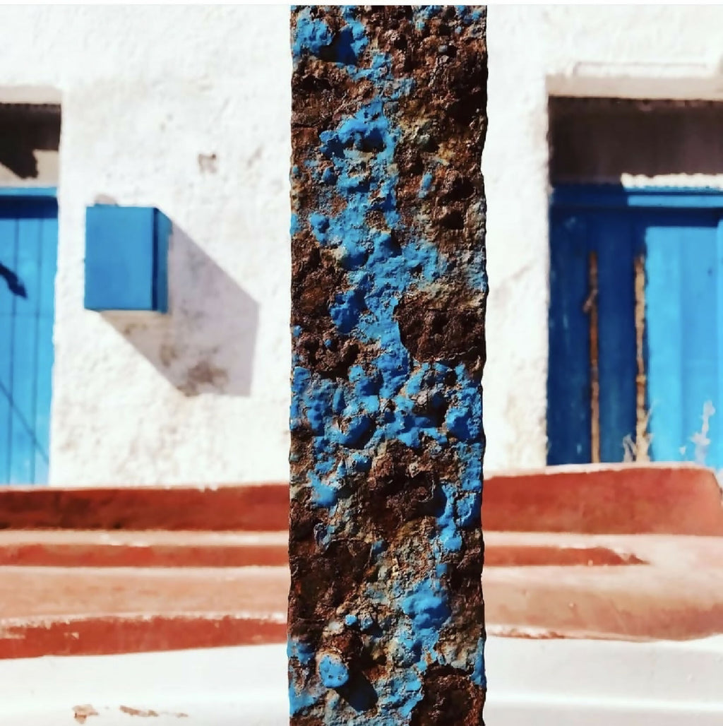 Livre de photographies : pilier peint avec texture bleue et brune, devant un bâtiment.