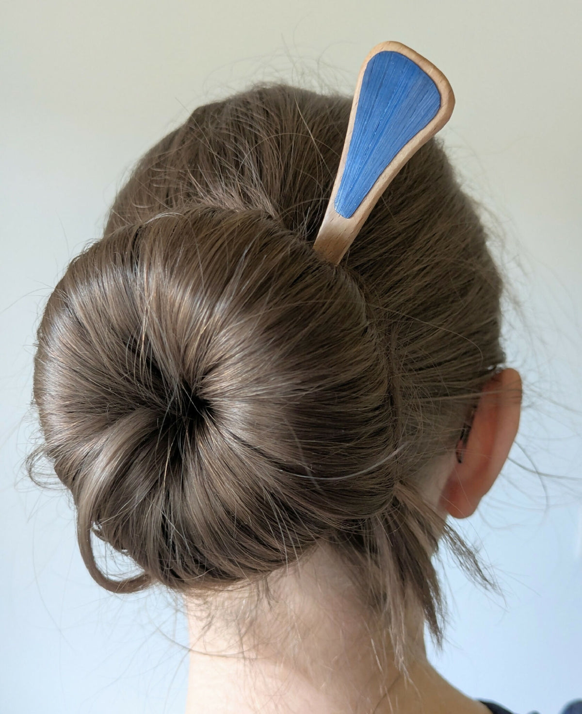 Pic à chignon en bois avec marqueterie paille bleue, fixé dans un chignon