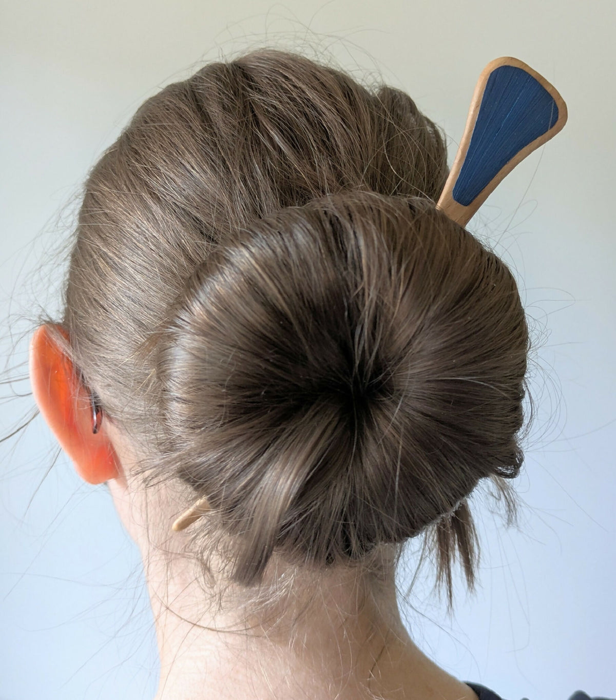 Pic à chignon en bois à marqueterie paille bleue, vu de profil sur cheveux