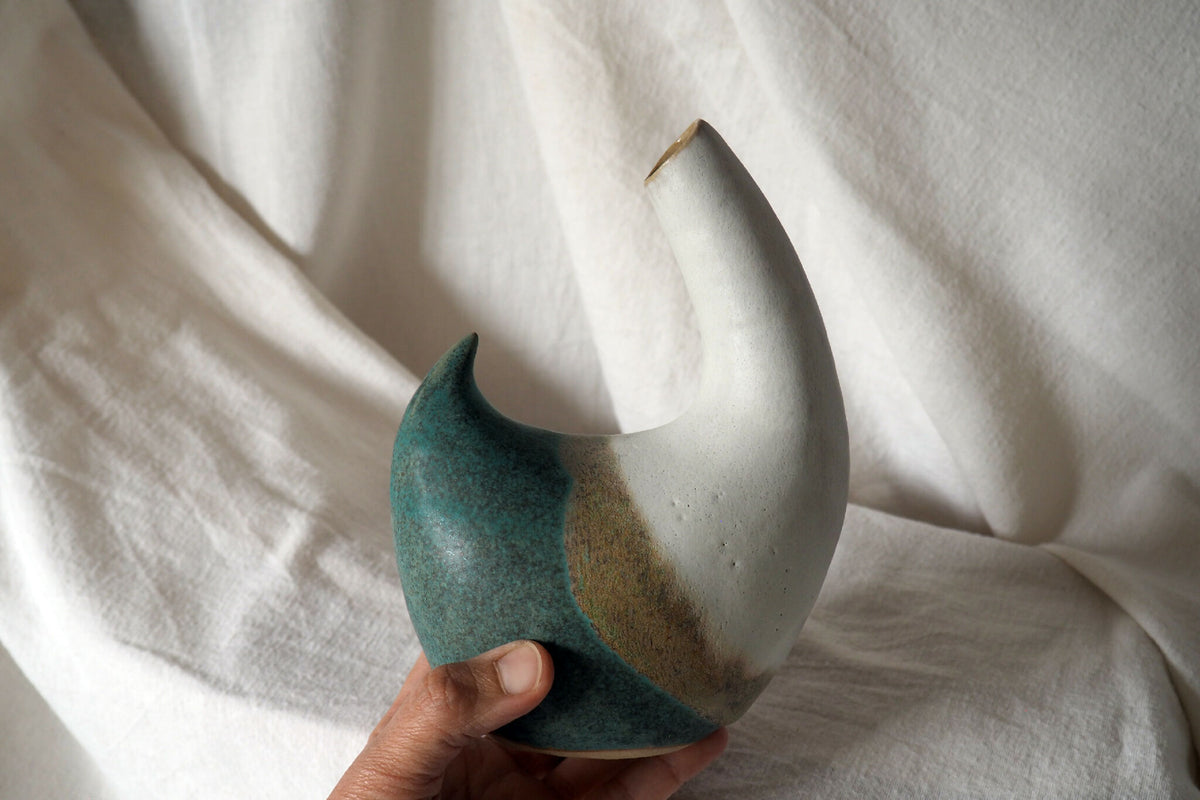Pichet en céramique bicolore blanc et turquoise, tenu à la main, bec incurvé