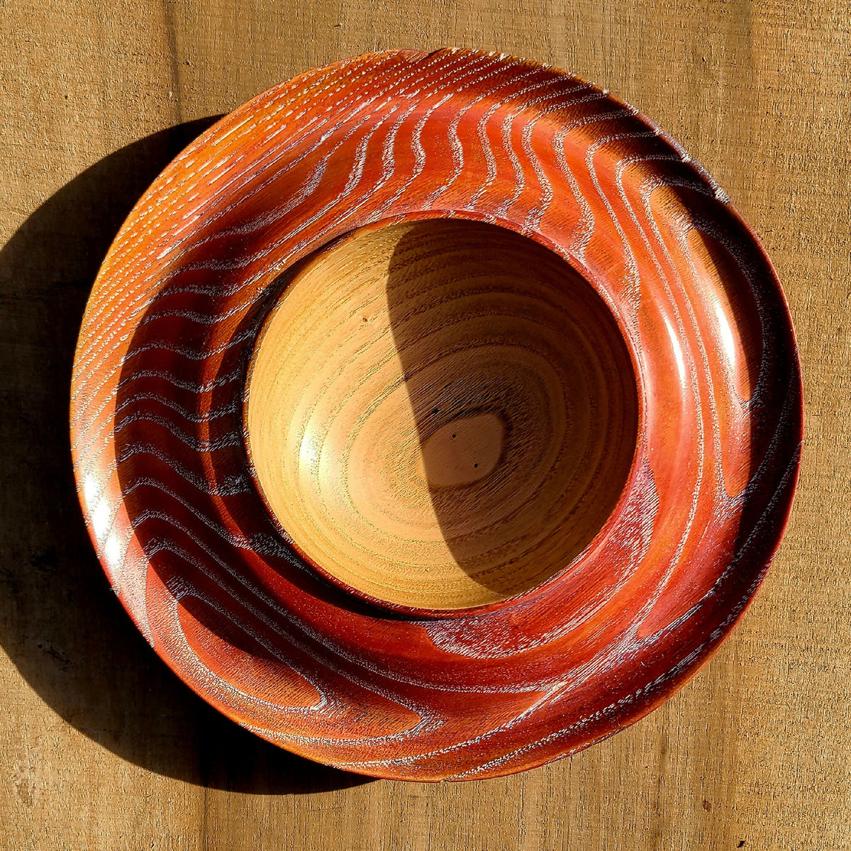 Coupe à fruits en bois, plateau circulaire orange à rayures, anneau central clair.