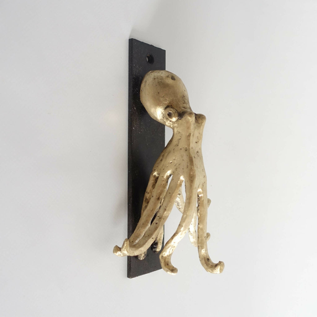 Porte-clés figurine pieuvre en métal doré sur plaque noire murale