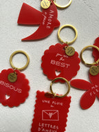 Ensemble de porte-clés rouges avec anneaux dorés, formes fleurs et carte, messages d’amour.