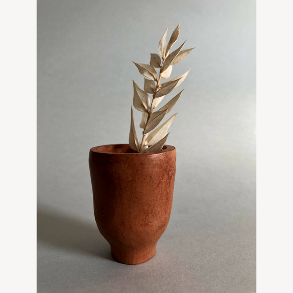 Petit pot haut en terre cuite et bouquet de feuilles séchées.