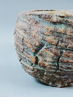 Pot en grès turquoise et brun, gros plan sur le relief strié et la texture rugueuse.