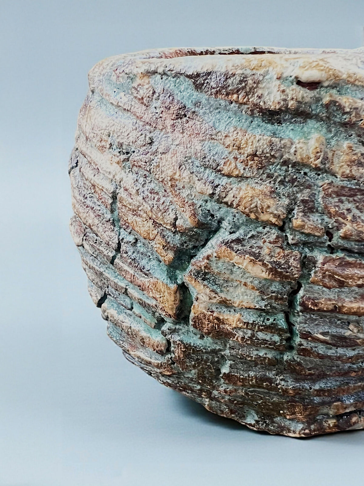 Pot en grès turquoise et brun, gros plan sur le relief strié et la texture rugueuse.