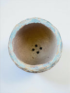 Base de pot en grès bleu turquoise, intérieur brun, trois trous de drainage visibles.