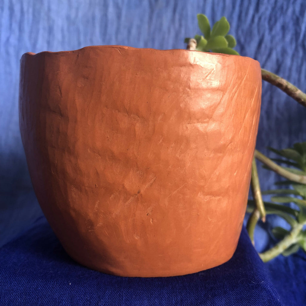 Pot en métal cuivré rouge, vue latérale rapprochée, texture martelée.