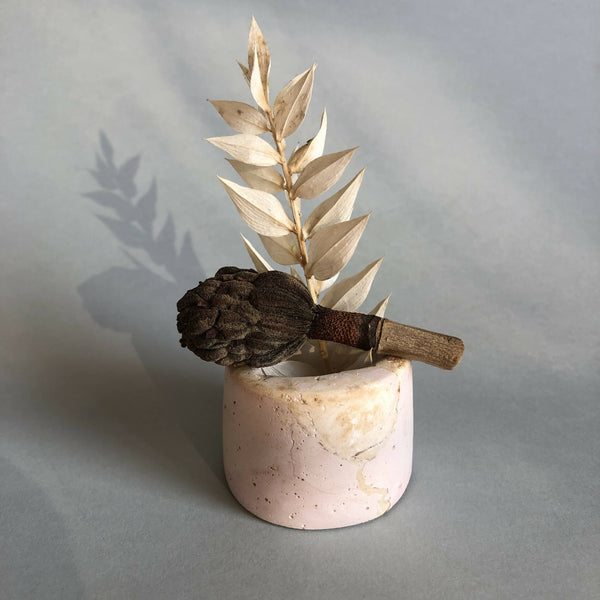 Petit pot en céramique rose pâle avec tige de feuilles dorées et fleur brune