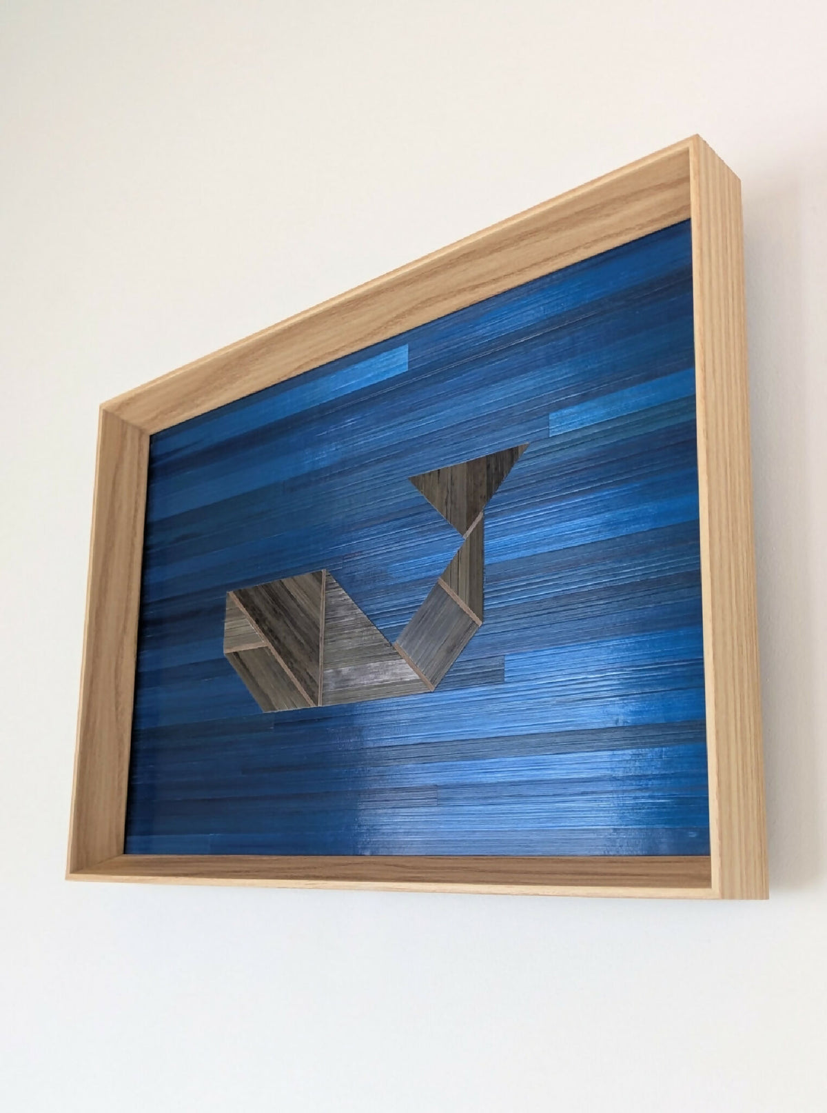 Tableau tangram en marqueterie, cadre bois clair, bleu roi et éléments gris