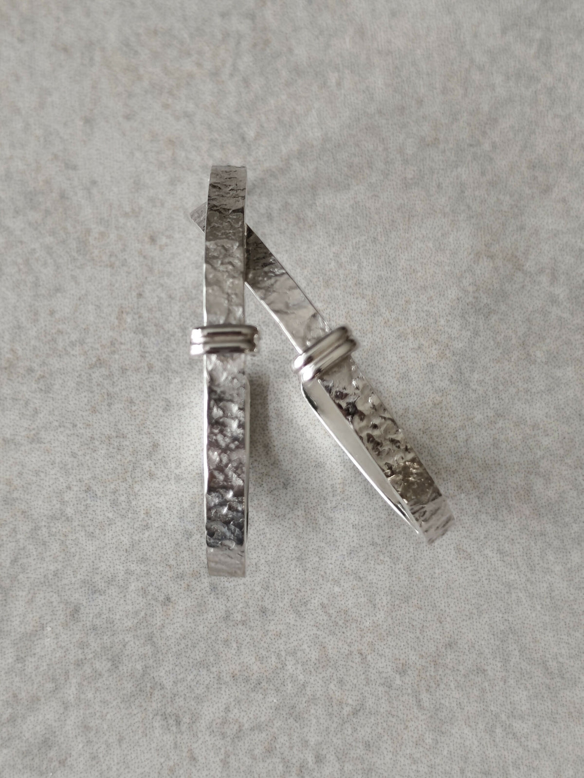 Boucles d’oreilles courbes argentées, une vue latérale sur la texture martelée