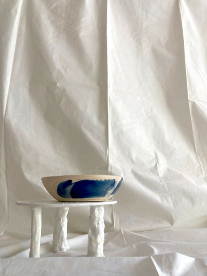 Petit bol en grès blanc à motif bleu, posé sur trois pieds.